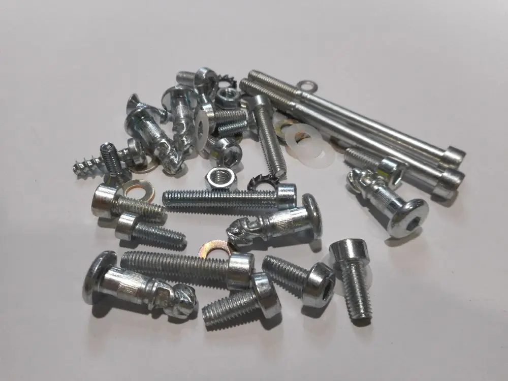 Verschiedene metallene Schrauben, Bolzen und Unterlegscheiben von Remeha auf einem weißen Hintergrund, unordentlich angeordnet.